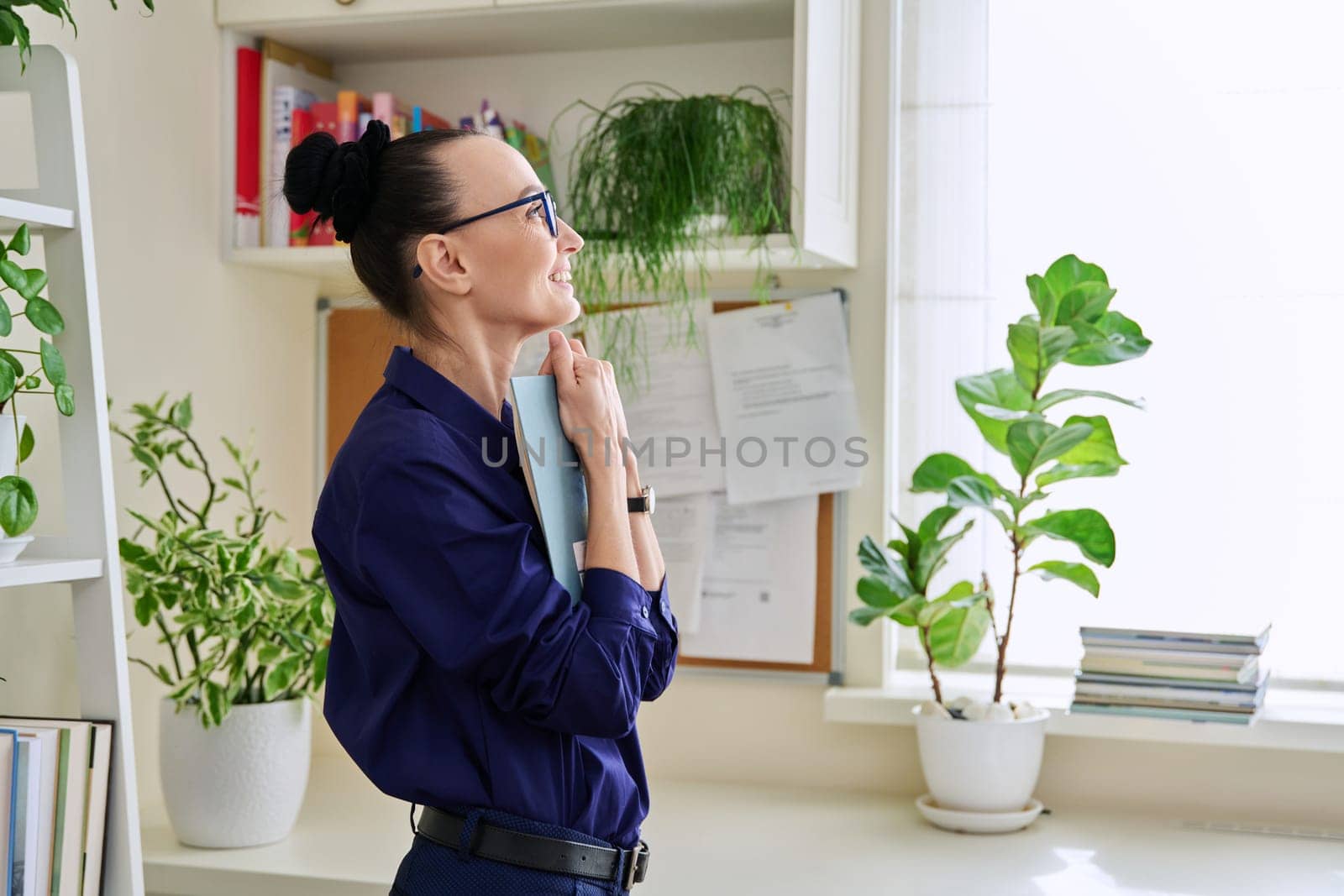 Middle-aged woman reading fiction book at home, at home near window by VH-studio