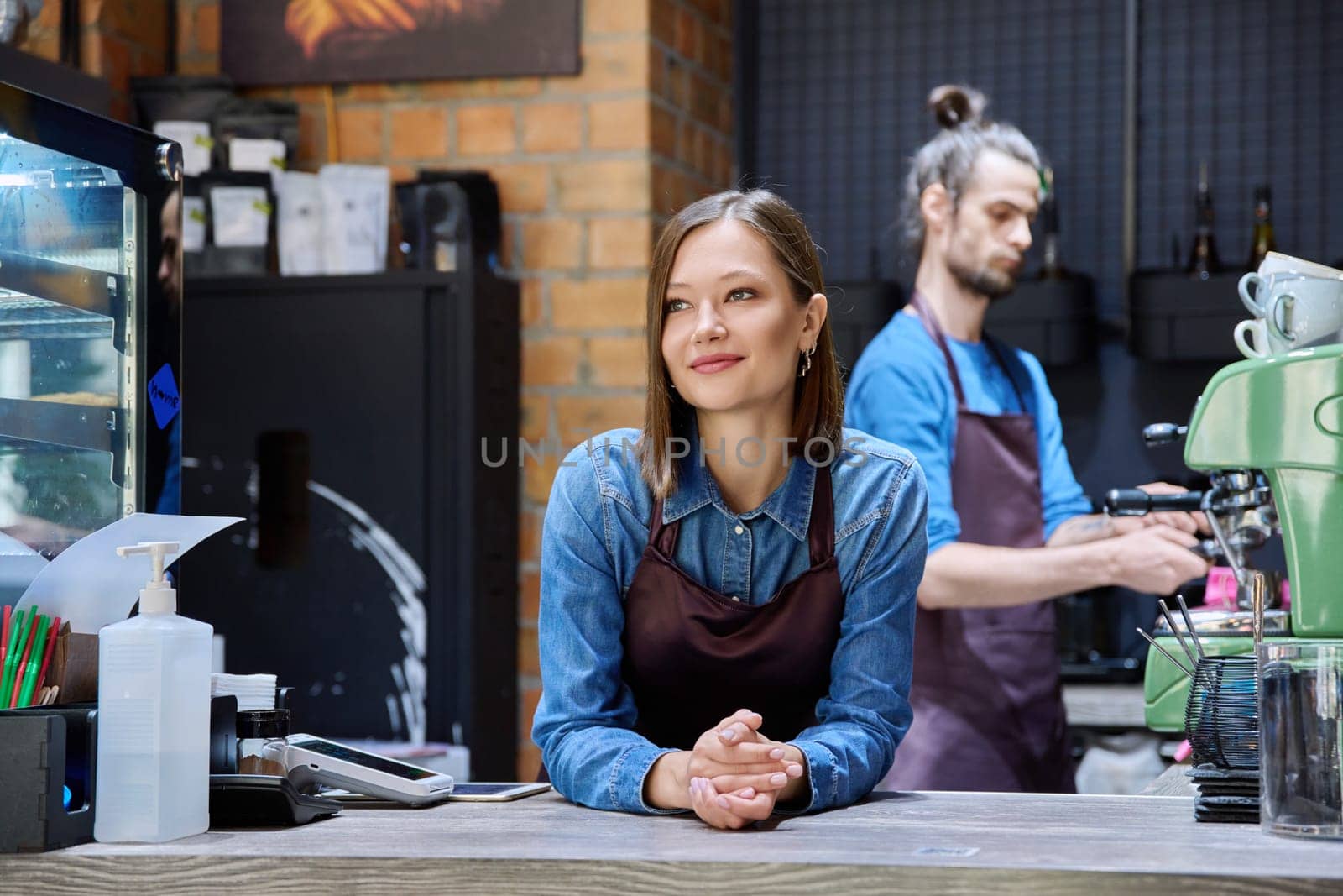 Colleagues partners young man and woman in aprons working together in coffee shop by VH-studio