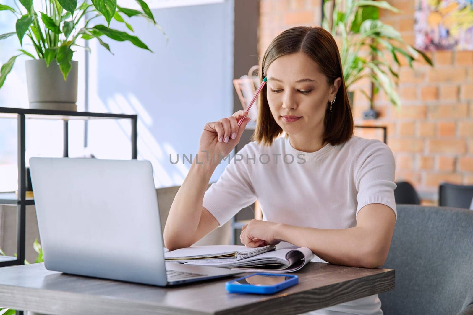 Female college student studying using laptop, sitting in coworking cafe by VH-studio