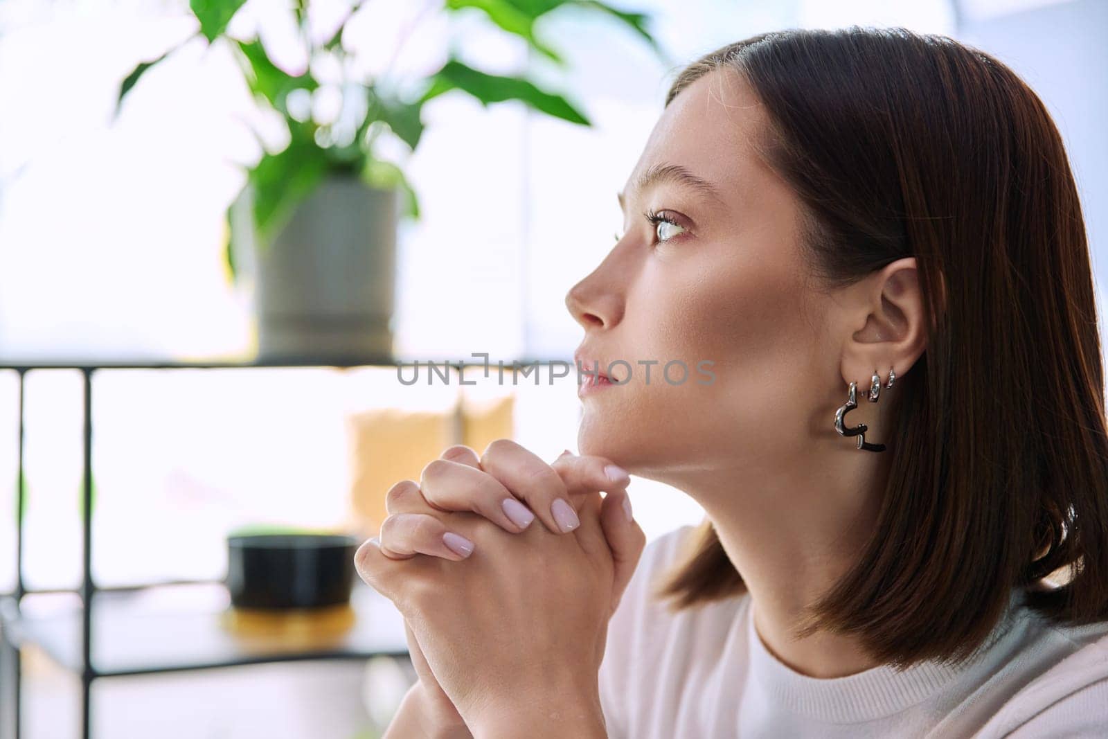 Excited sad upset serious young woman with folded hands, face in profile close-up. Emotions stress depression troubles difficulties, mental health, youth lifestyle concept