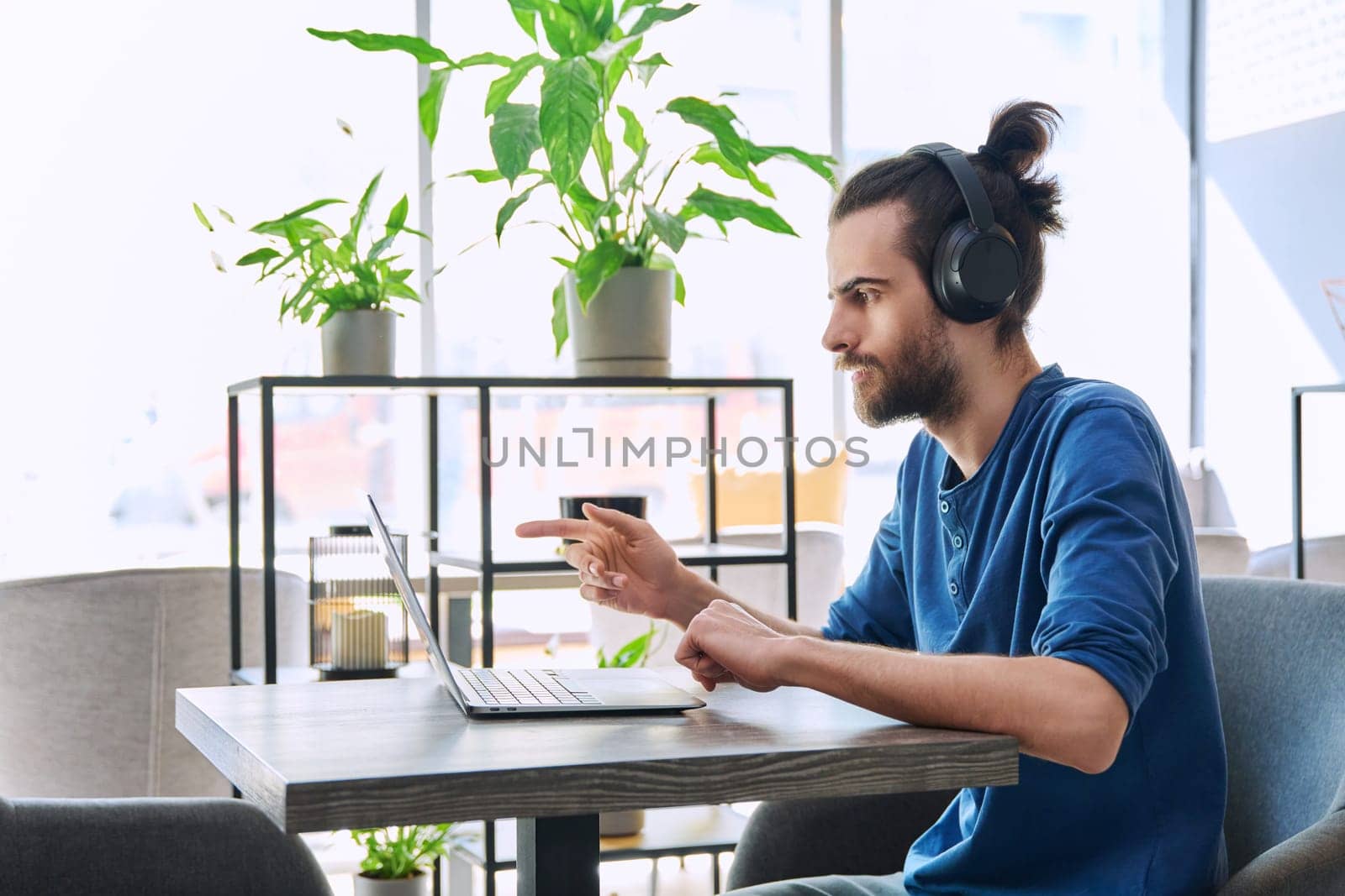 Young handsome man in headphones having work video chat using laptop by VH-studio