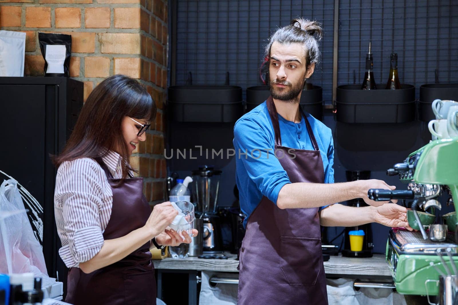 Teamwork, man and woman in aprons working together at bar counter in coffee shop cafe by VH-studio