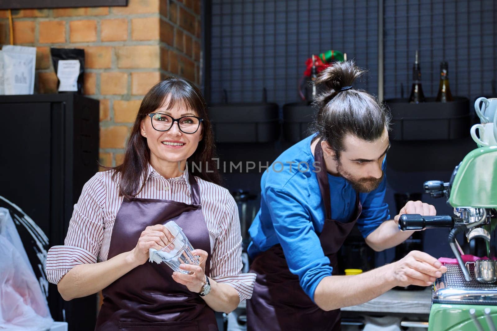 Teamwork, man and woman in aprons working together at bar counter in coffee shop cafe by VH-studio