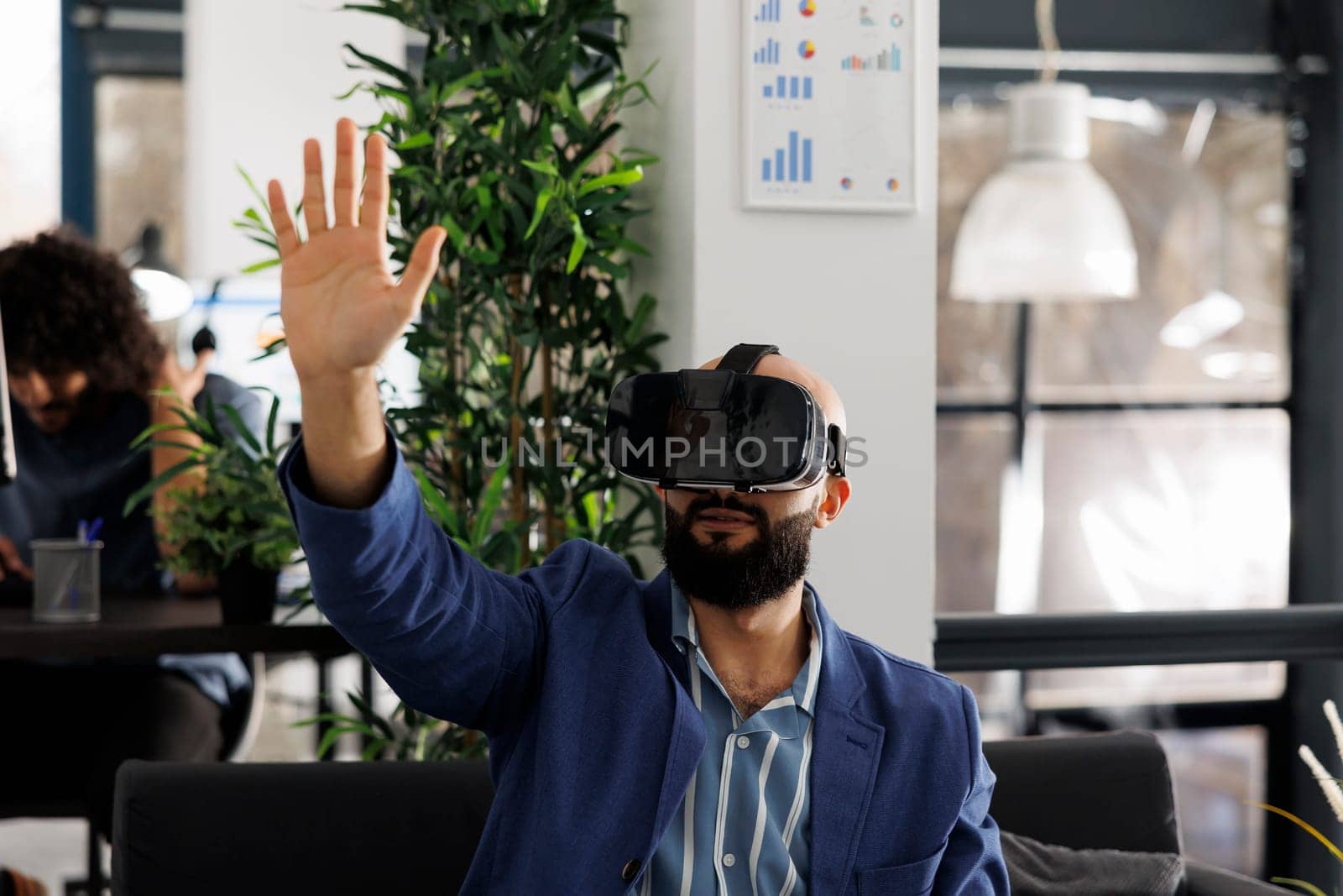 Businessman in virtual reality headset working in start up business office. Company employee exploring metaverse and brainstorming in vr glasses in corporate coworking space