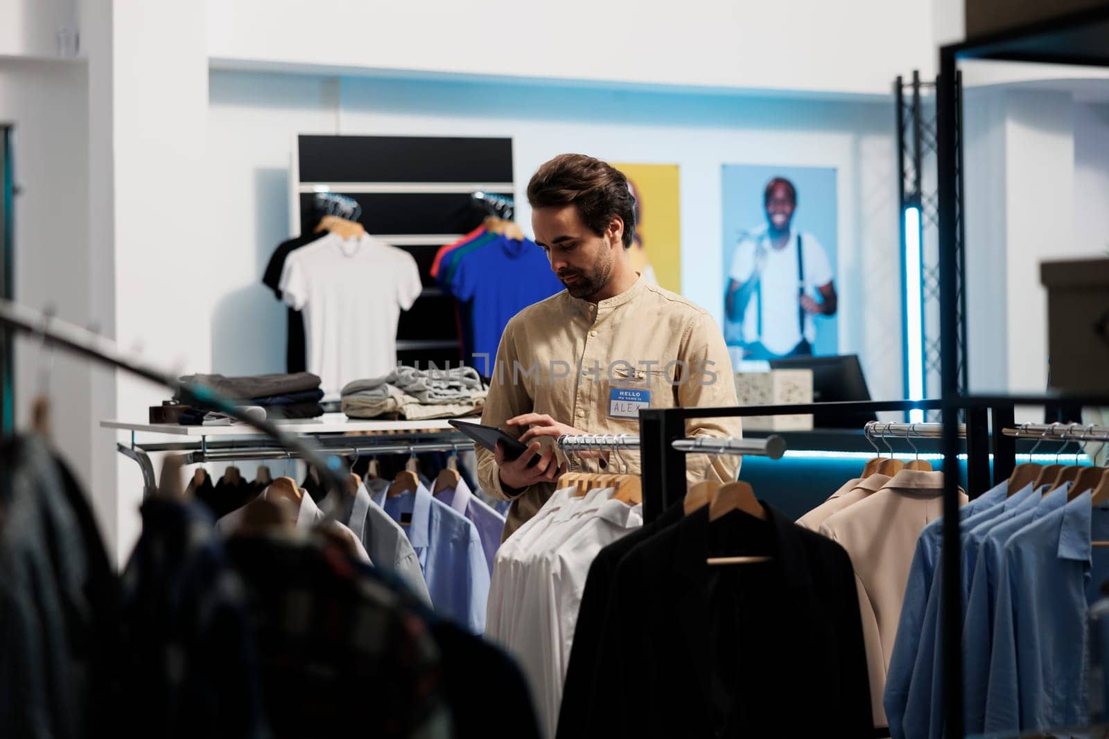 Clothing store caucasian man employee checking garment stock availability on digital tablet. Shopping center fashion outlet manager updating merchandise information on website