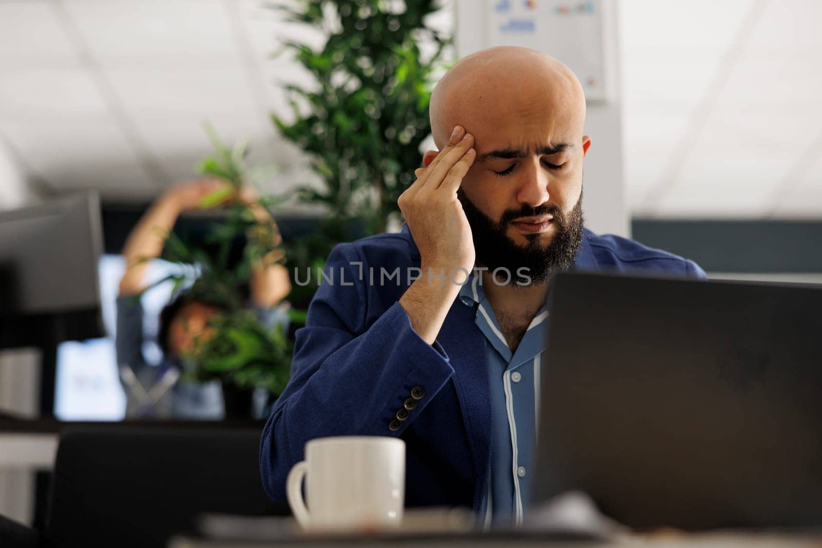 Tired arab businessman with headache working in business office by DCStudio