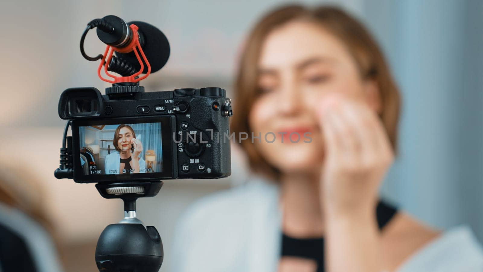 Rear view behide camera screen display influencer shoot live streaming vlog video review makeup prim social media or blog. Girl with cosmetics studio lighting for marketing recording session online.