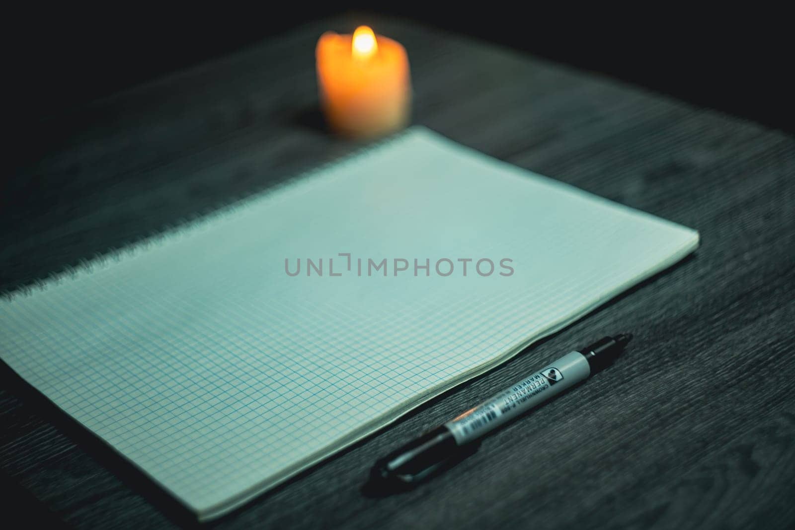 Large notebook and black marker in candlelight on the wooden table. High quality photo