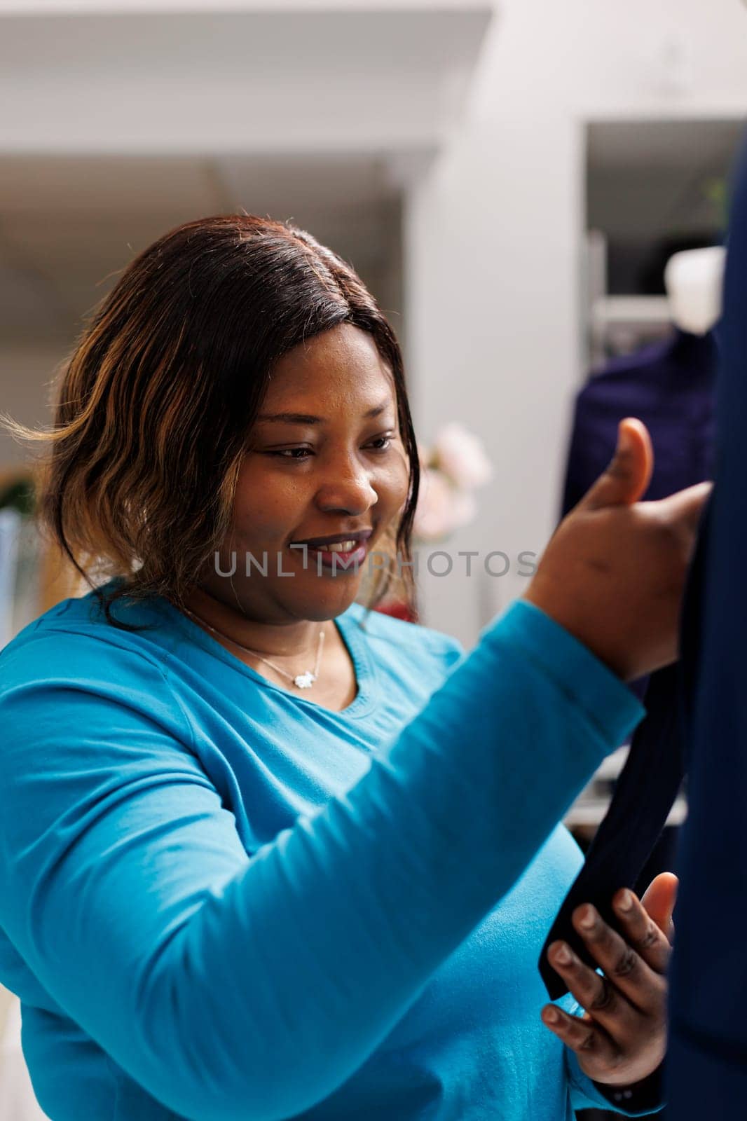 African american woman checking suit fabric in clothing store, looking at formal wear. Shopaholic woman shopping for fashionable merchandise analyzing new fashion collection in modern boutique
