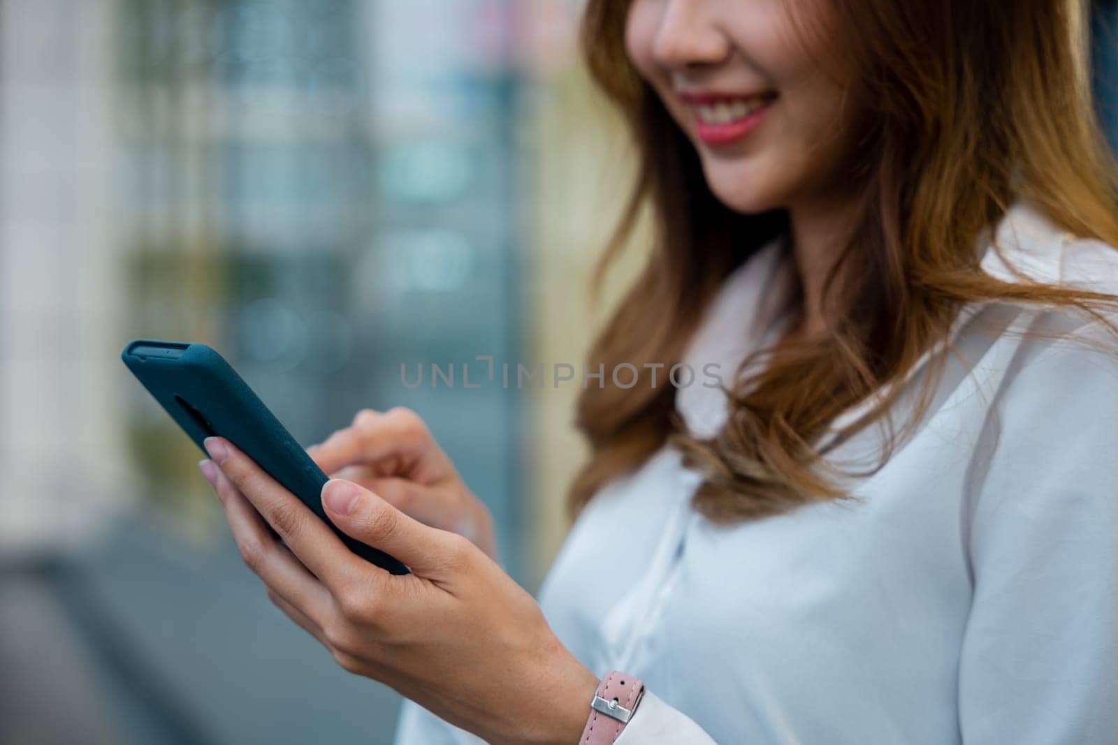 A woman in a white shirt using her smartphone for business by Sorapop