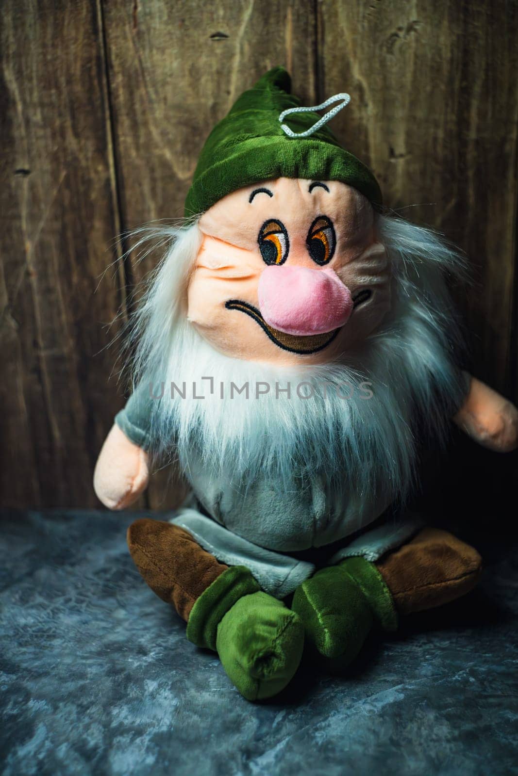 A toy gnome sits leaning on a wooden wall. High quality photo