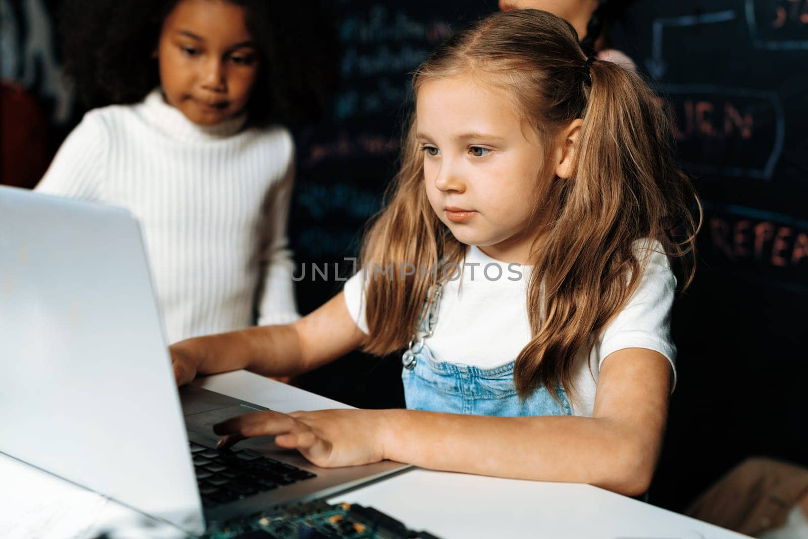 Schoolgirl in white bib learning robotics technology using laptop. Erudition. by biancoblue