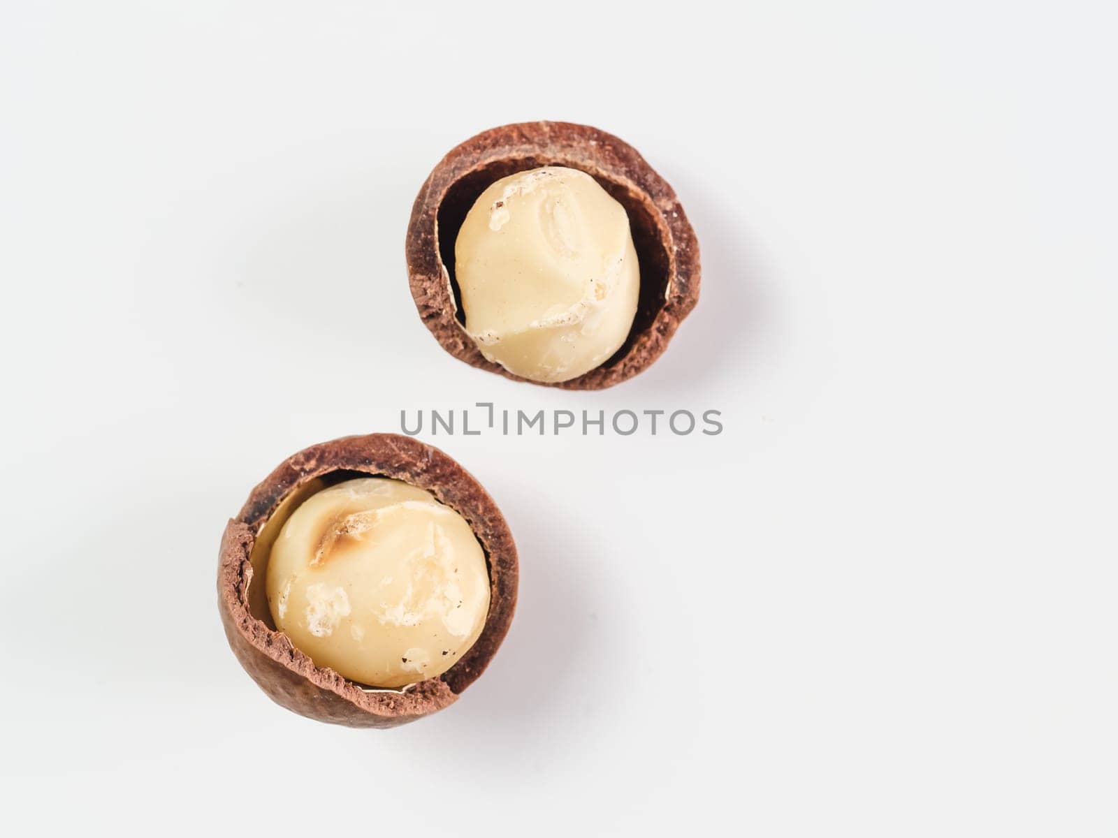 Two peeled macadamia nuts on white background. Set of two macadamia nuts with open shells, isolated on white, top view or flat lay. Copy space for text.