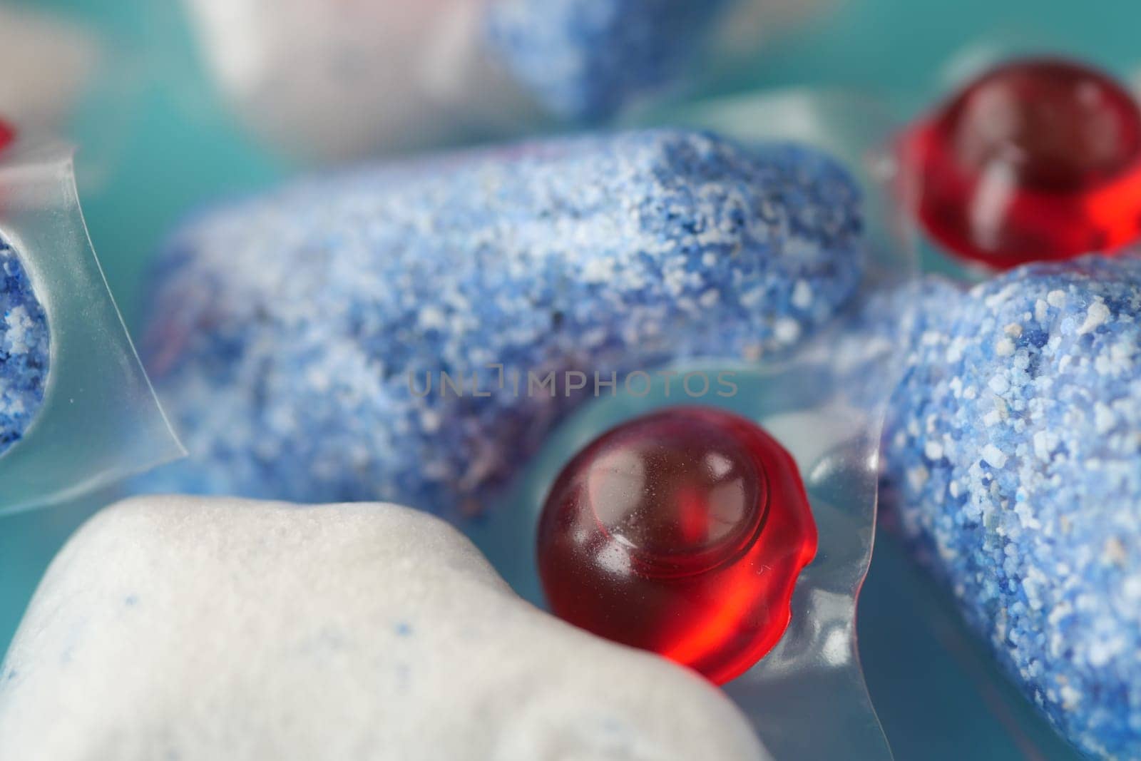 A stack of dishwasher tablets and a bottle of detergent on a blue background.