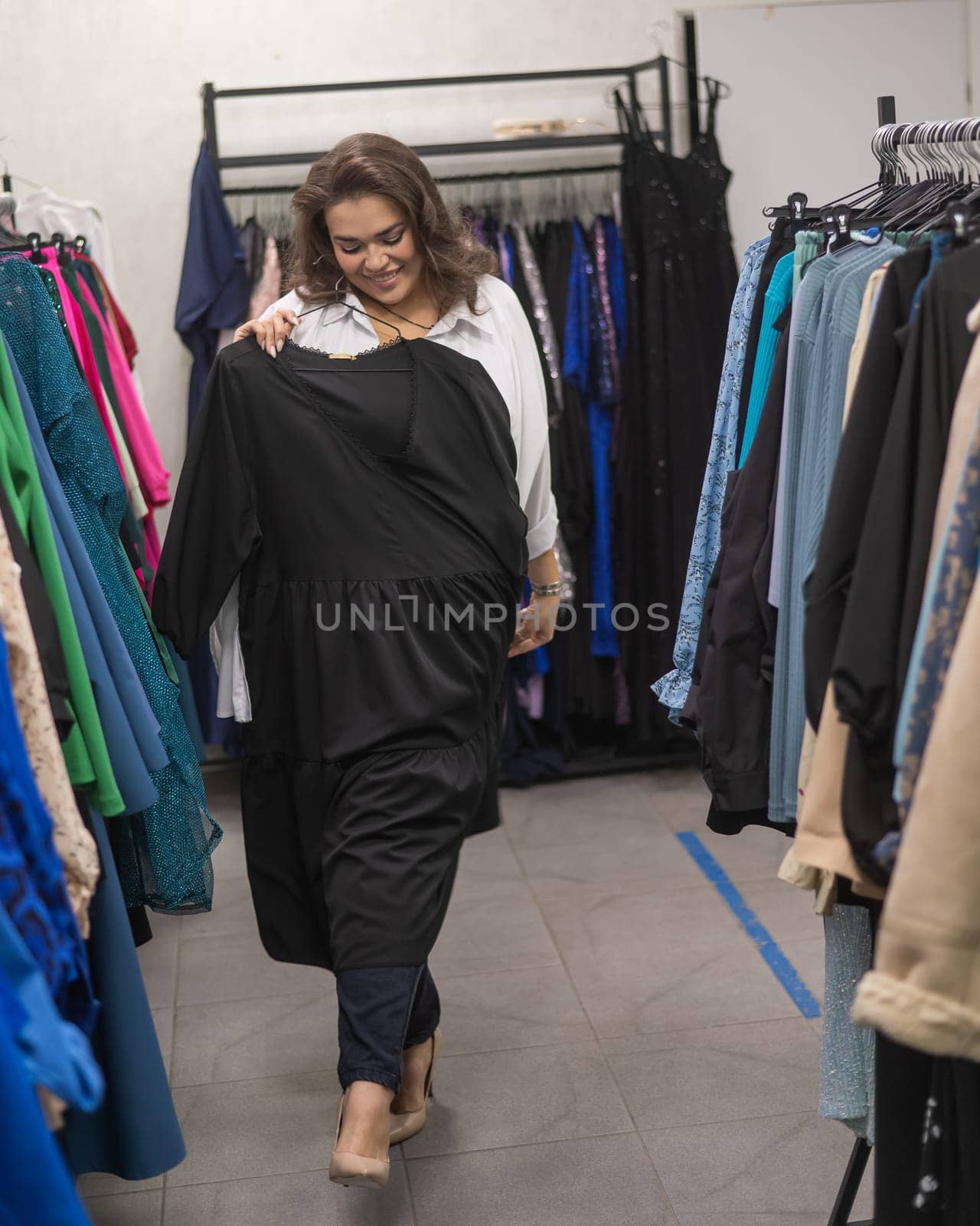 A fat woman in a plus size store tries on a black evening dress. Vertical photo. by mrwed54