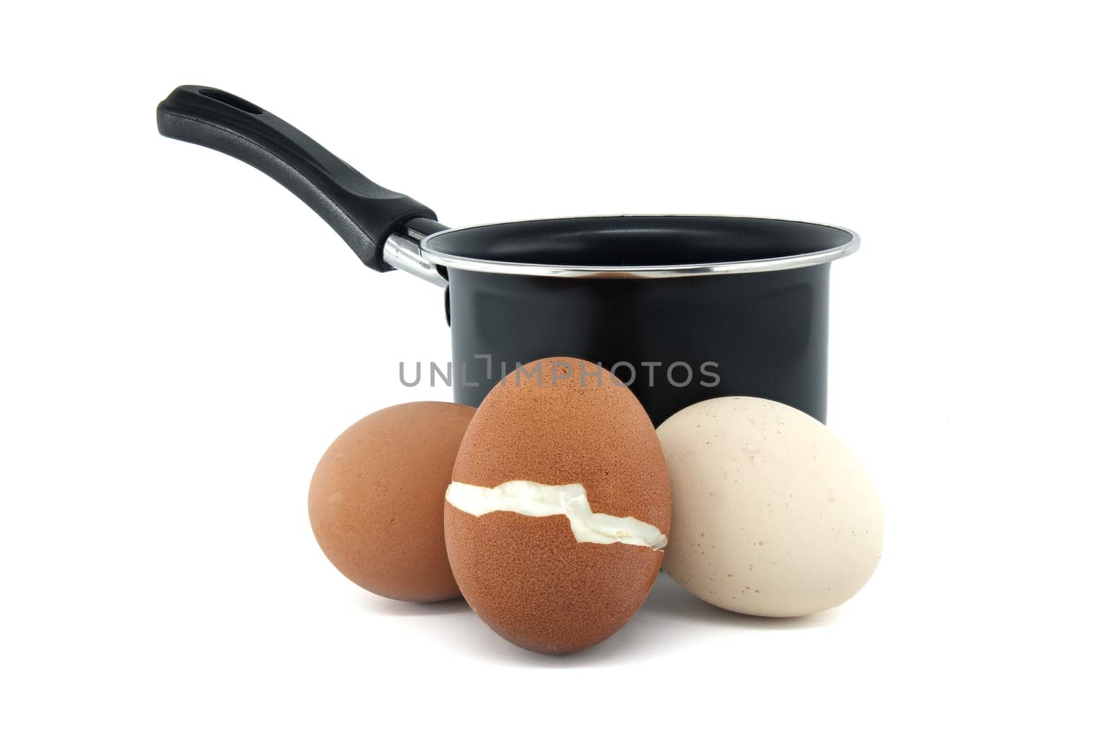Black cooking pot surrounding collection of eggs with varying colors, one egg has cracked during boiling, isolated on white background
