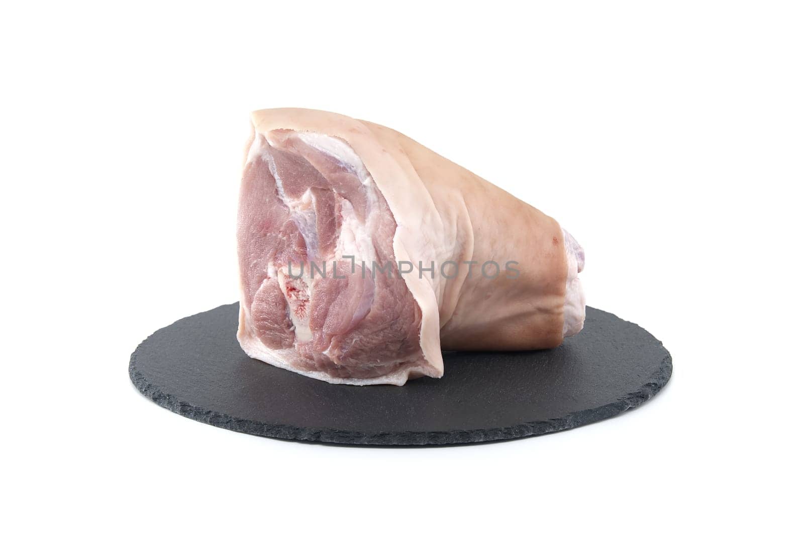 Fresh raw pork shank on black stone plate over white background