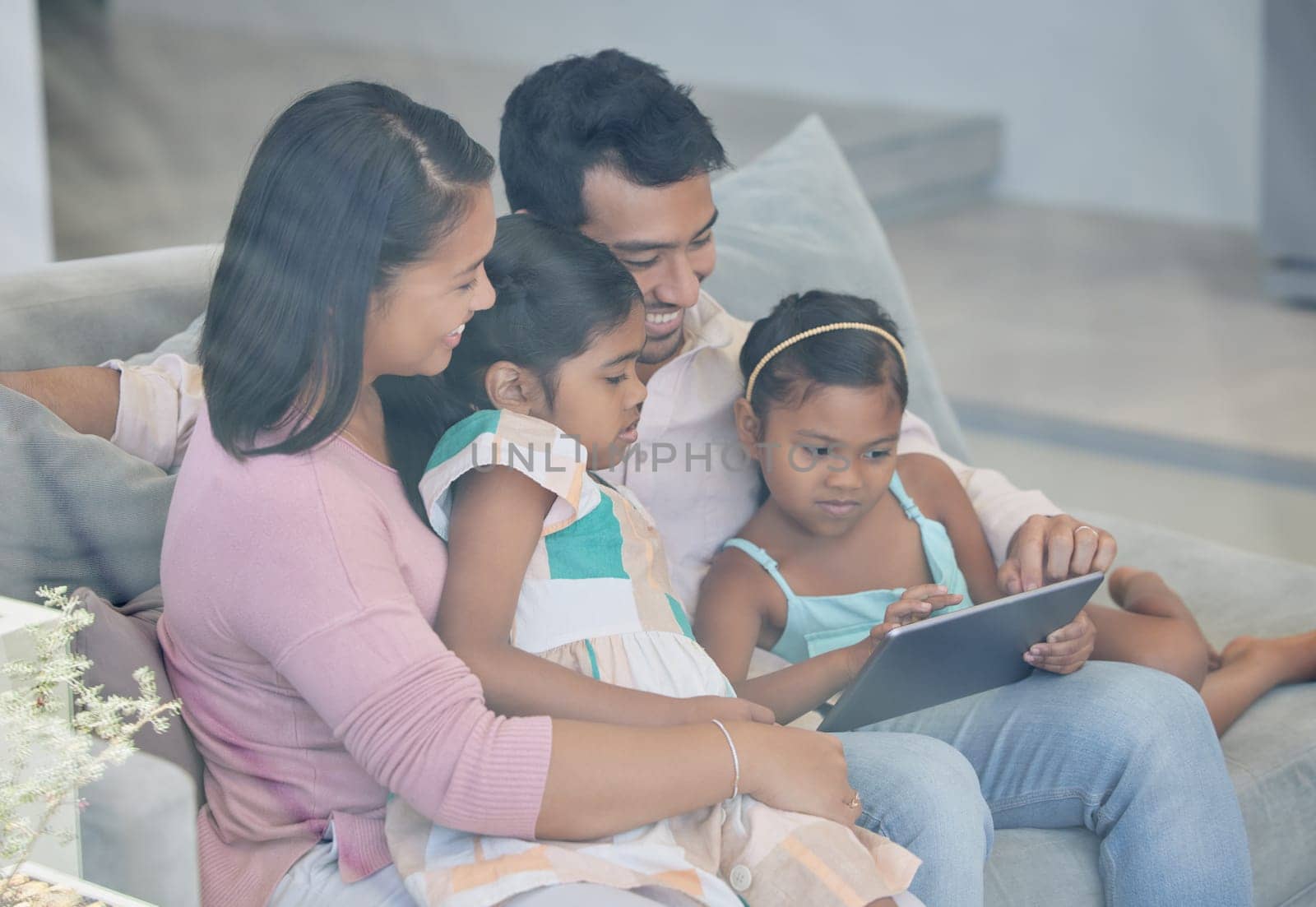 Technology, parents and children on couch with tablet, internet and relax together in living room. Mom, dad and girl kids on sofa with digital app for streaming, games and online connectivity in home by YuriArcurs