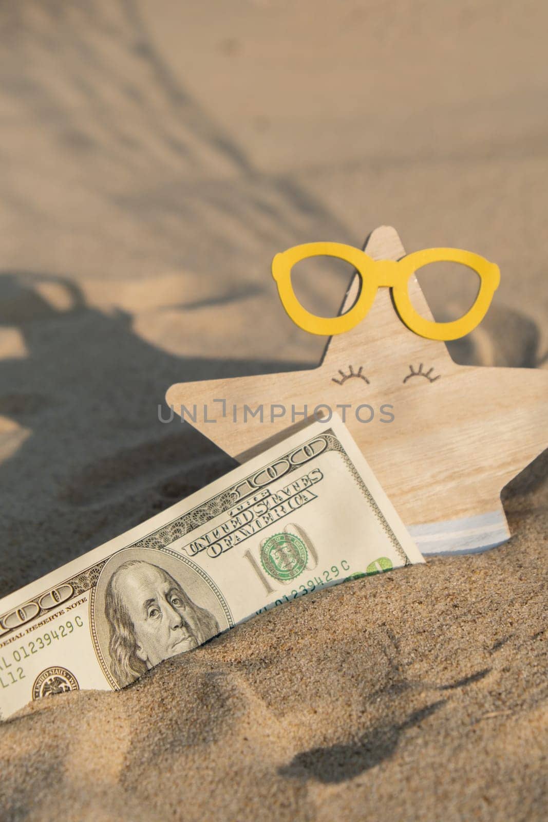 Money american hundred dollar bills in sandy beach with starfish. Concept finance saving money for holiday vacation. Costs in travel holidays. Shadows