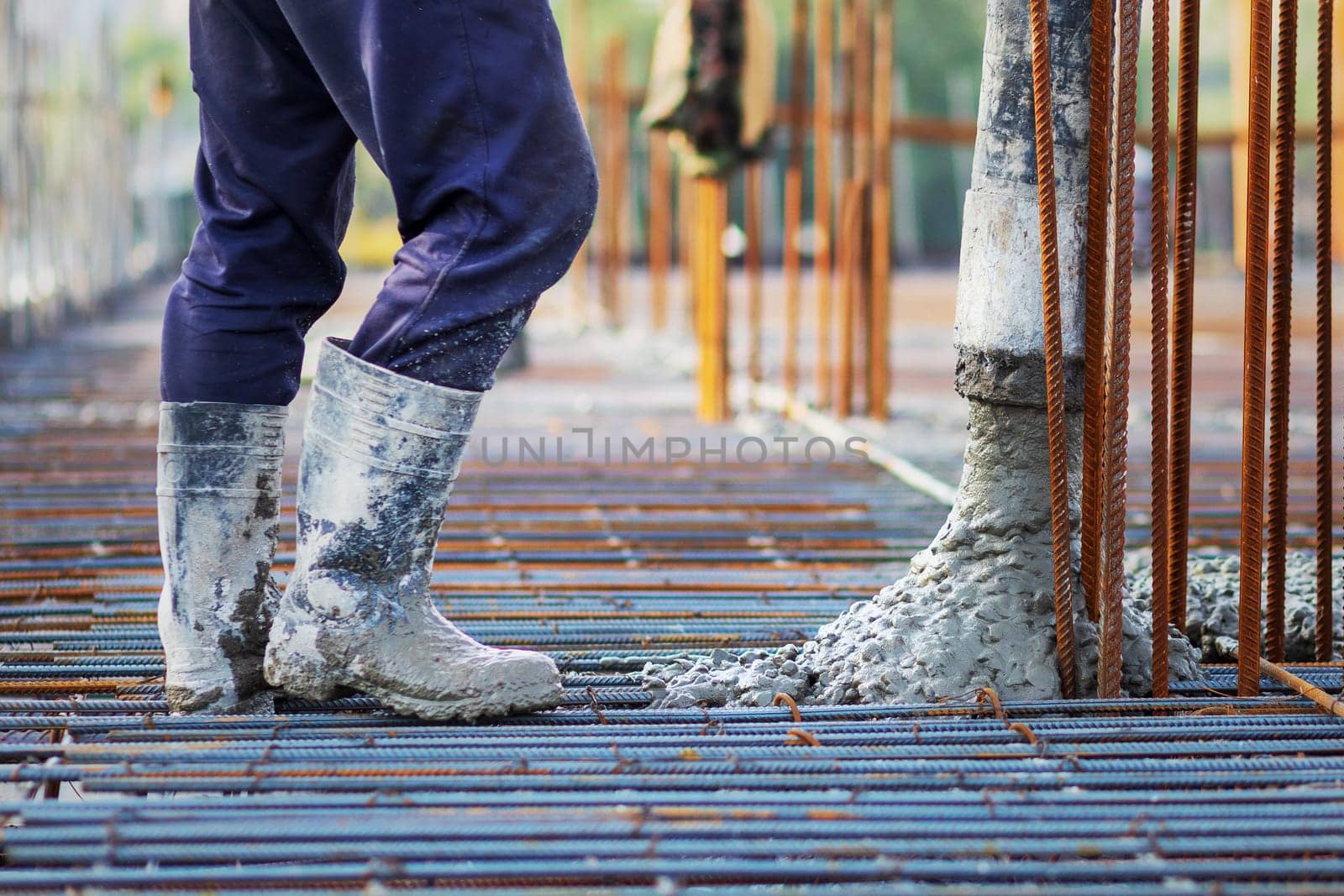 Concrete is poured into a steel reinforcement frame at a construction site by Rom4ek