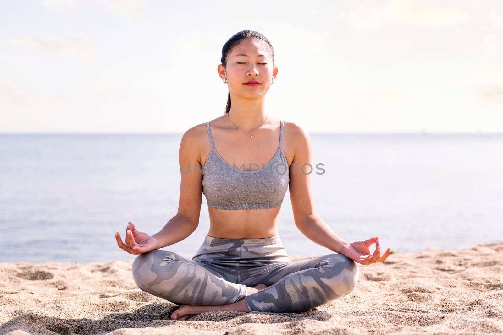 young asian woman doing meditation at beach by raulmelldo