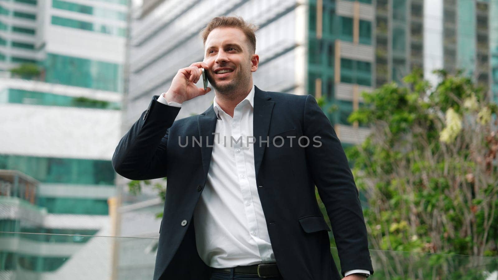 Businessman standing at rooftop while talking with team by using phone. Urbane by biancoblue