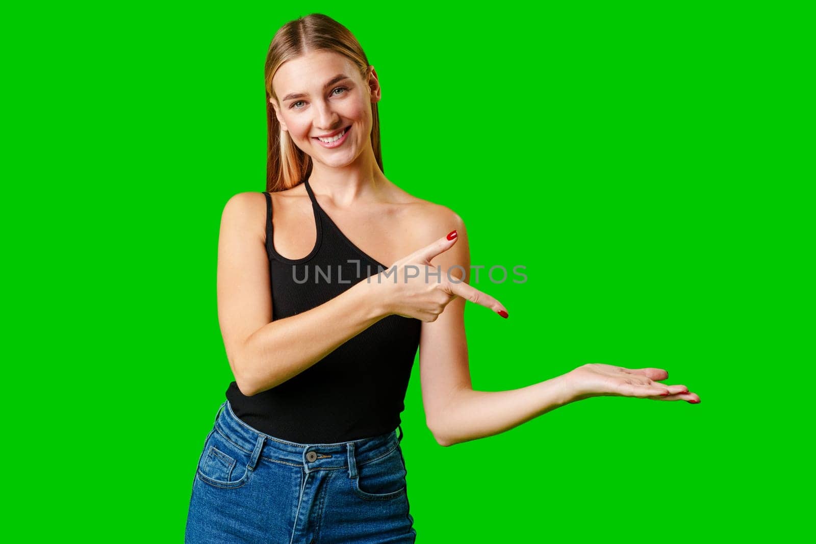 Young Woman Pointing at Something against green background in studio