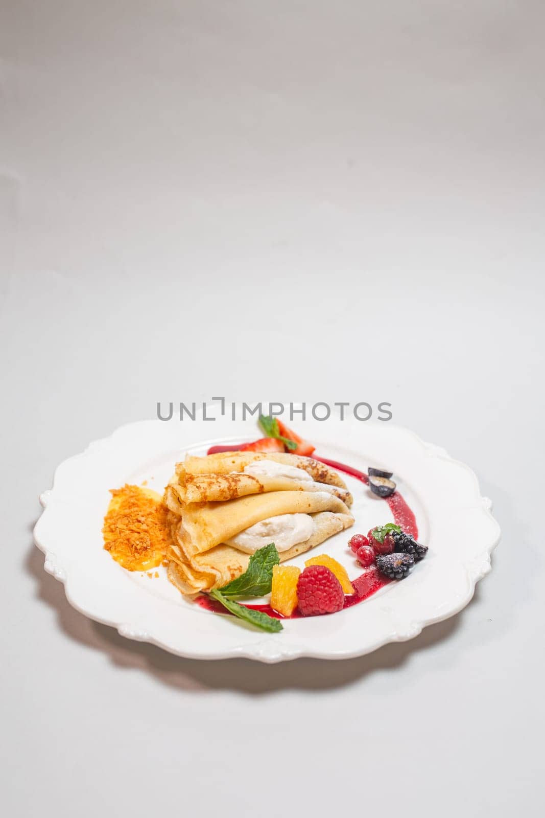 Delicious pancakes with berry and cream filling and jam on a white background. by Pukhovskiy