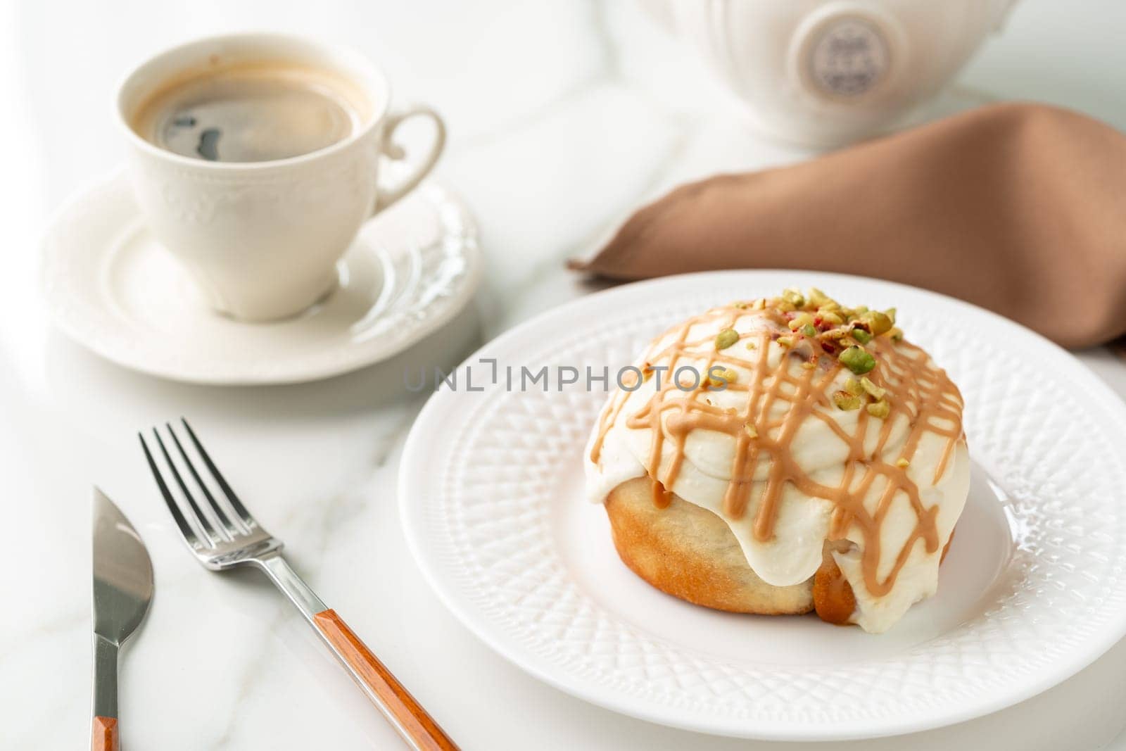 Cinnamon roll bun with icing on plate by Fabrikasimf