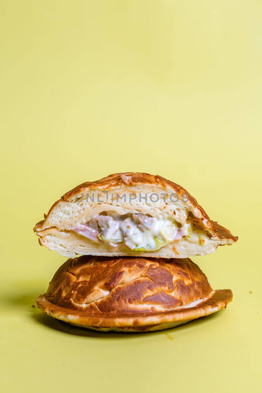 Half of burger with no top bread isolated on pastel yellow background by Pukhovskiy