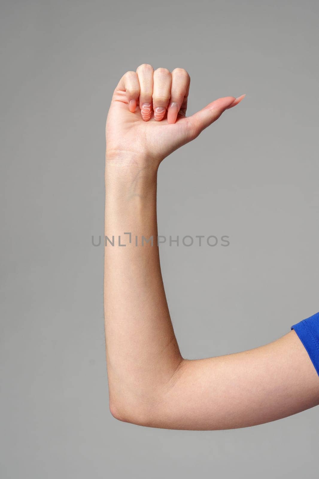 Female hand sign against gray background in studio by Fabrikasimf