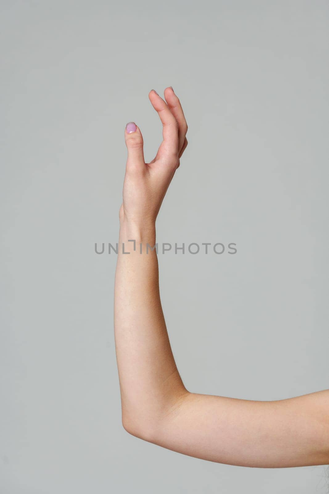 Female hand sign against gray background in studio close up