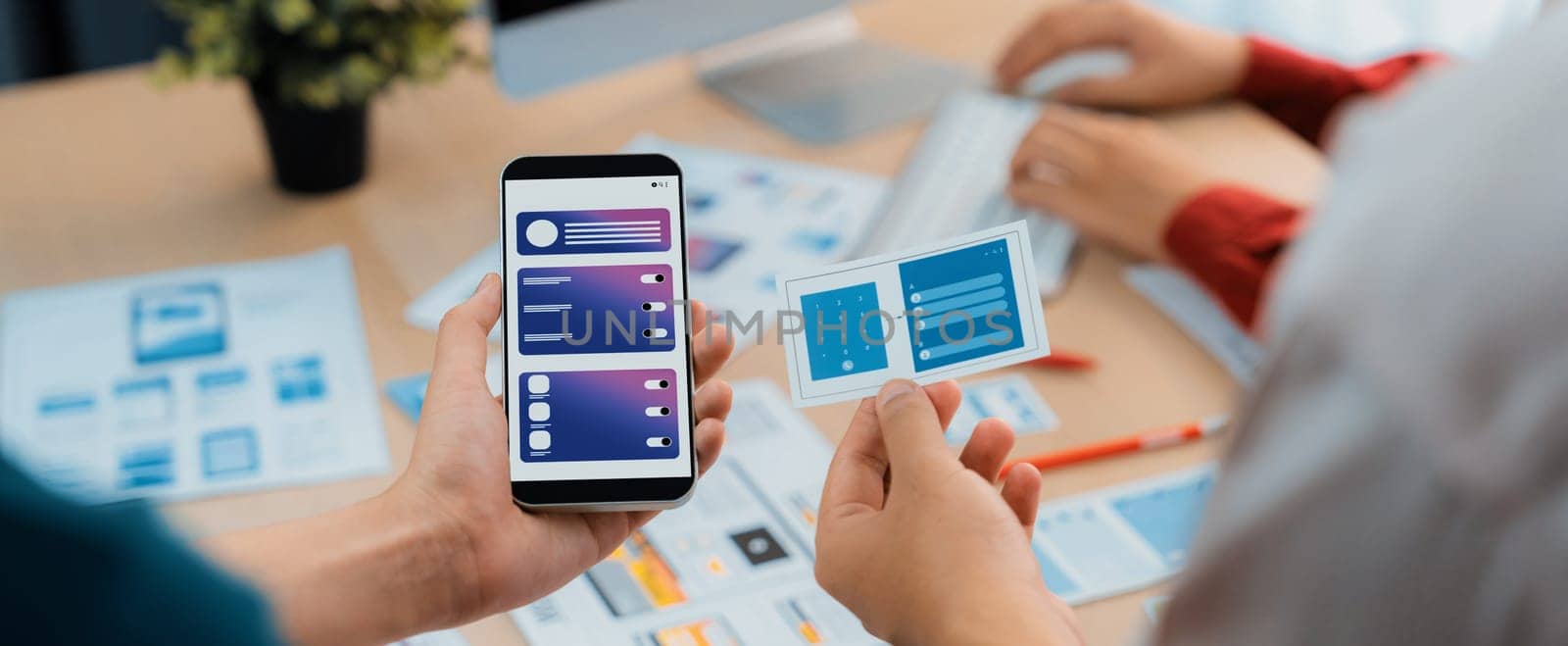 Panorama banner of startup UX developer or company employee design user interface or UI prototype for mobile application or website software with software display on smartphone in office. Synergic