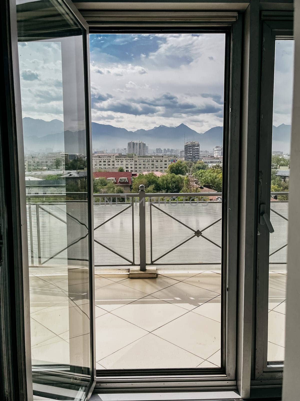 A stunning panoramic view of the city skyline and snow-capped mountains framed by an open door, creating a picturesque scene.