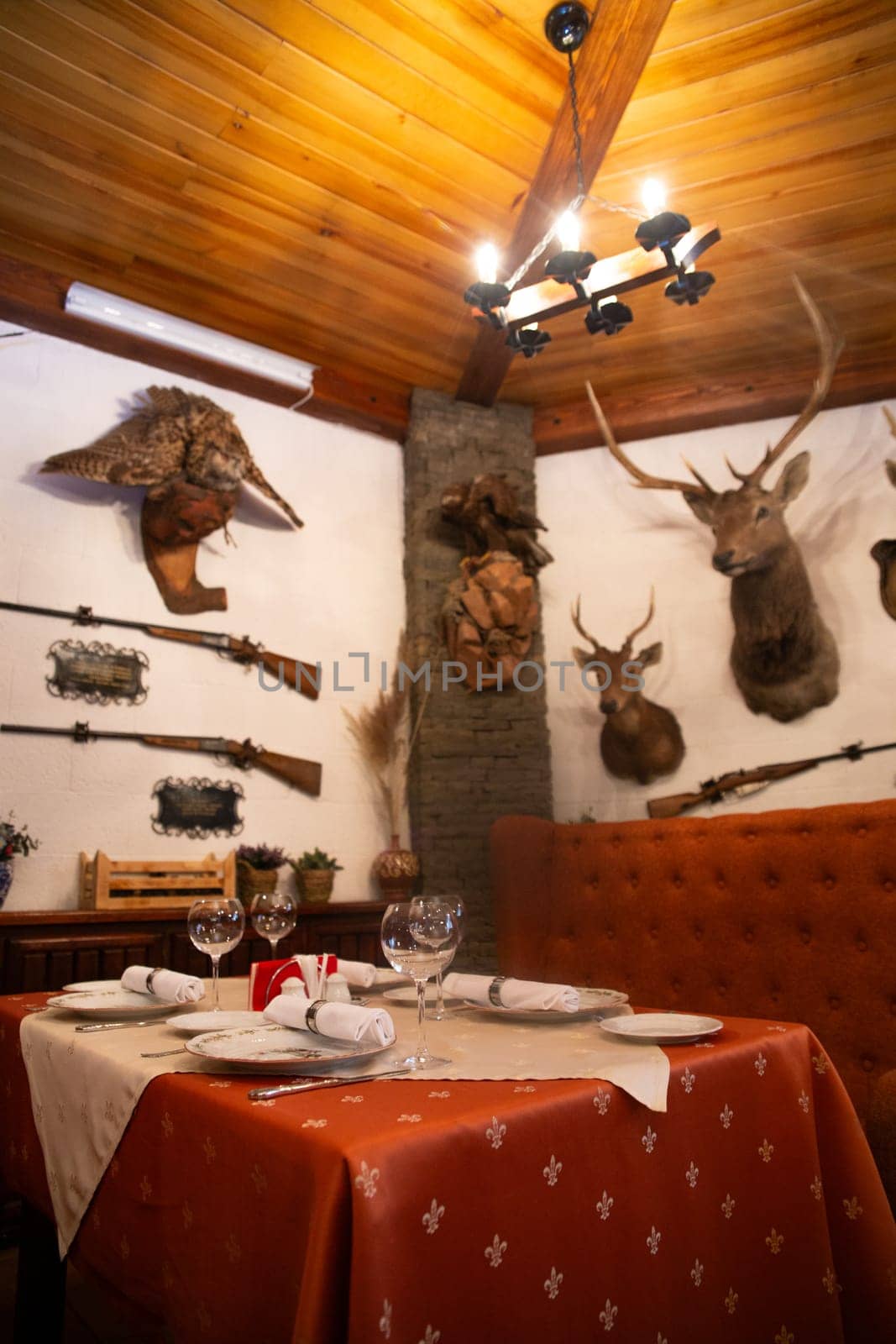 The interior of the restaurant with stuffed animals in a rustic style with a table set for a meal by Pukhovskiy