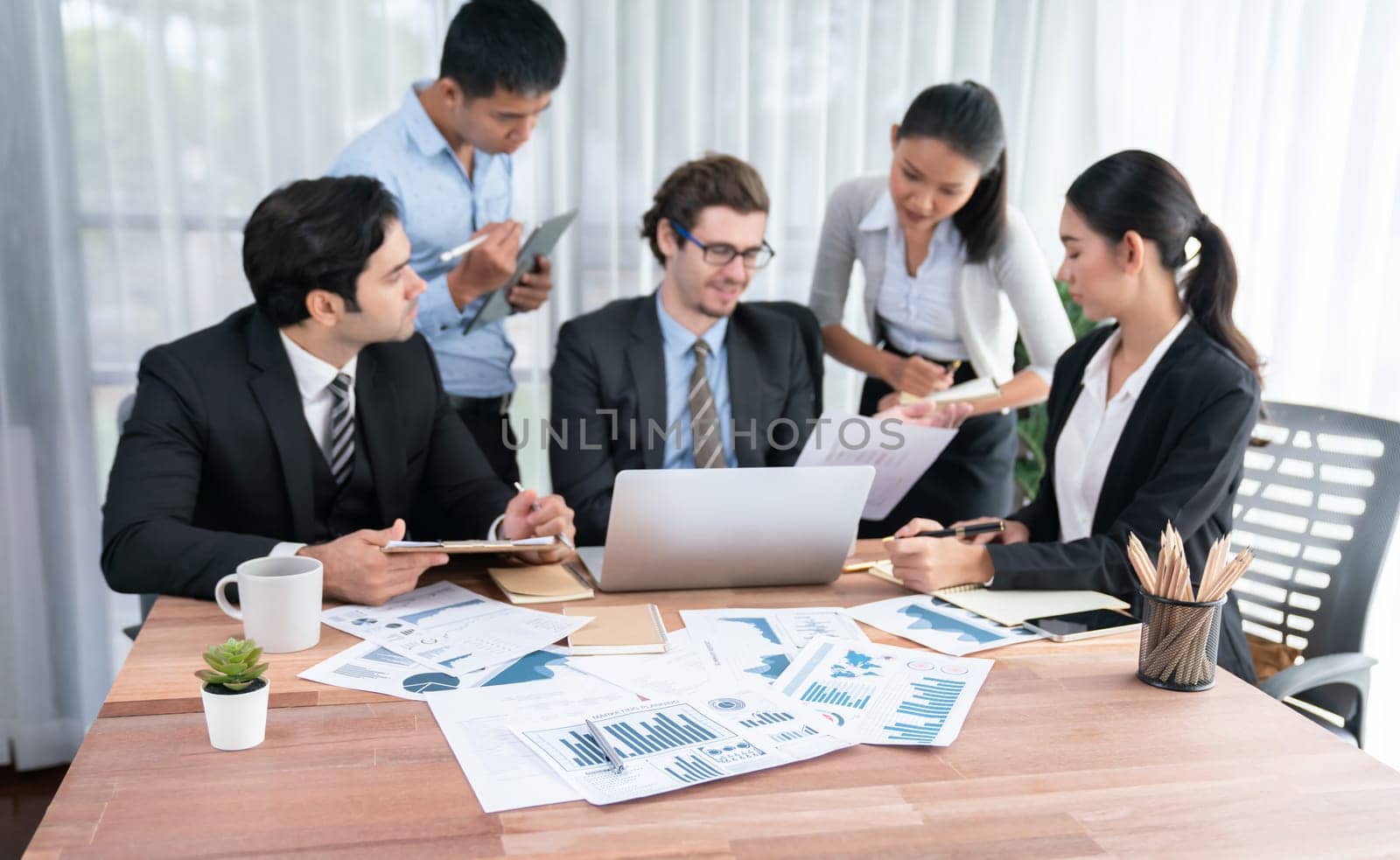 Diverse group of business analyst team analyzing financial data report paper on office table. Chart and graph dashboard by business intelligence analysis for strategic marketing planning Habiliment