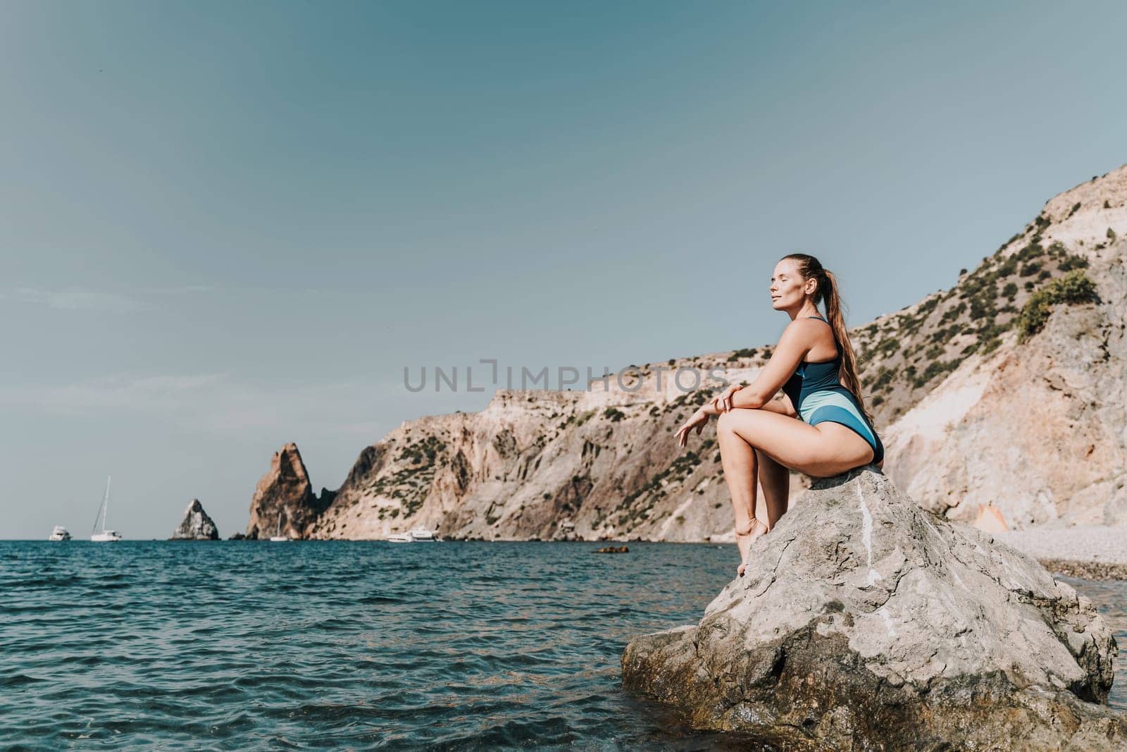 Woman beach vacation photo. A happy tourist in a blue bikini enjoying the scenic view of the sea and volcanic mountains while taking pictures to capture the memories of her travel adventure. by Matiunina