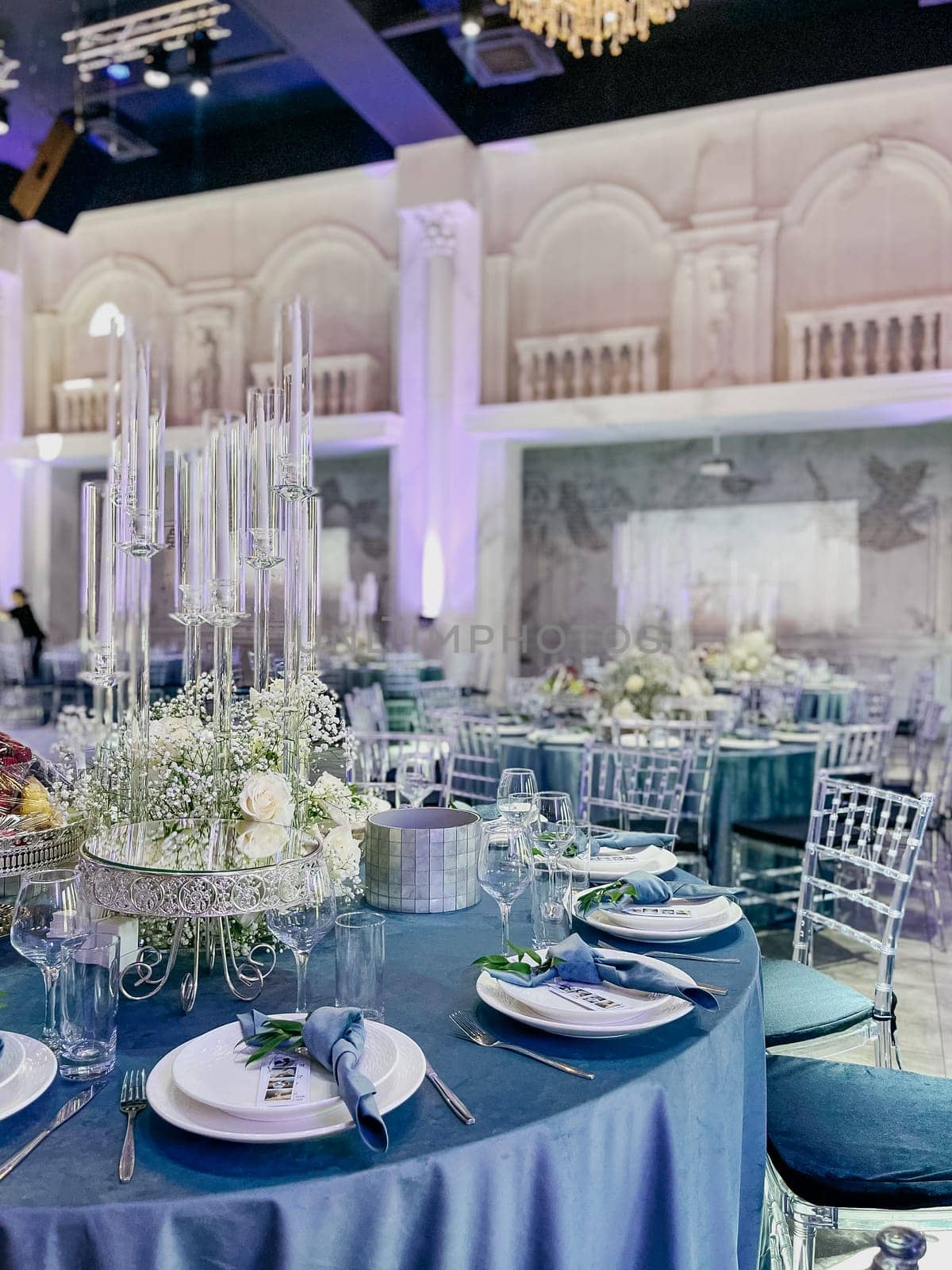 Elegant wedding reception hall with round tables and floral centerpieces by Pukhovskiy
