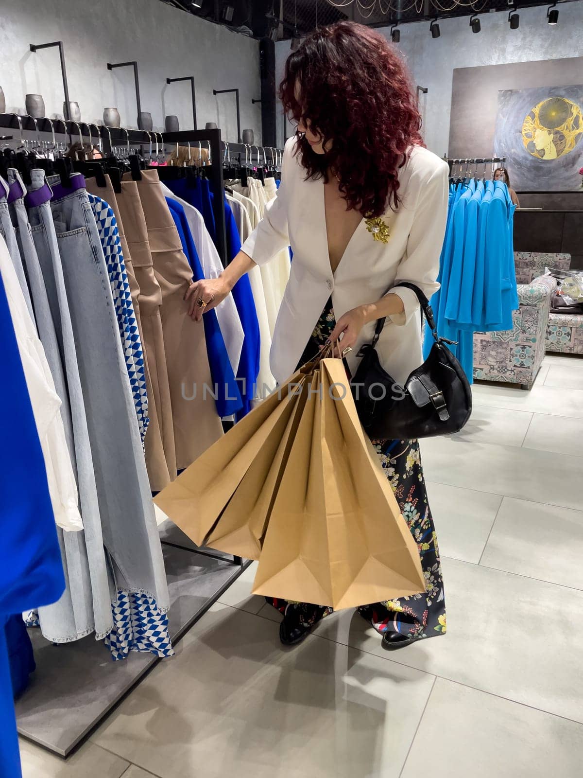 Shopping woman, women's fashion clothes in a store, boutique. Woman choosing clothes in a store by Matiunina