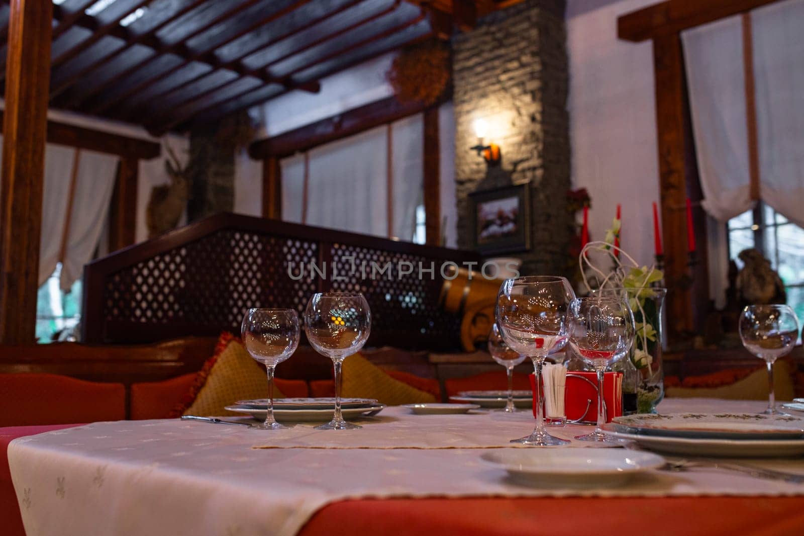 The image shows an elegant restaurant table setting with wine glasses and a bottle on the table with a blurred background of the restaurant.