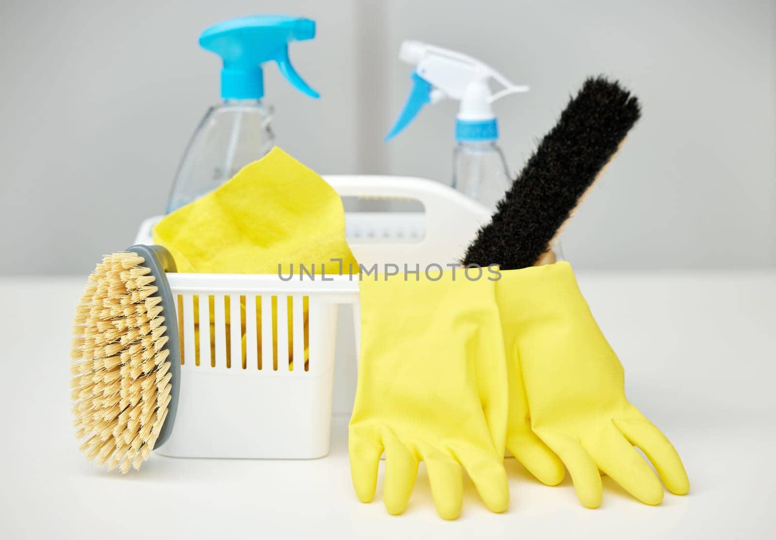 Table, brush or basket with cleaning supplies, spray bottle or chemical for bacteria, wellness or dirty mess. Grey background, maid service or ready for washing with product, liquid soap or gloves.