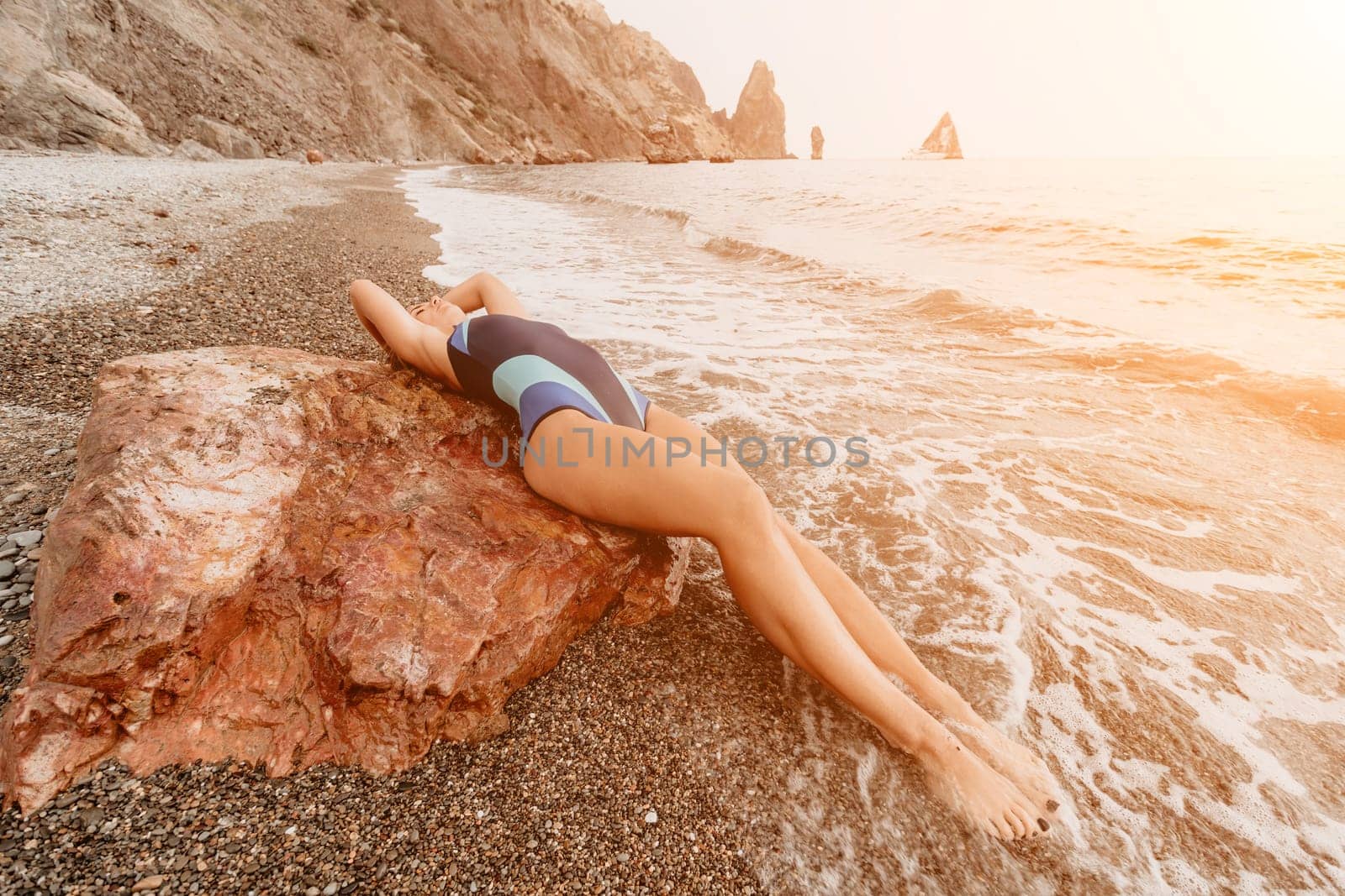 Woman summer travel sea. Happy tourist in blue bikini enjoy taking picture outdoors for memories. Woman traveler posing on the beach surrounded by volcanic mountains, sharing travel adventure journey by panophotograph