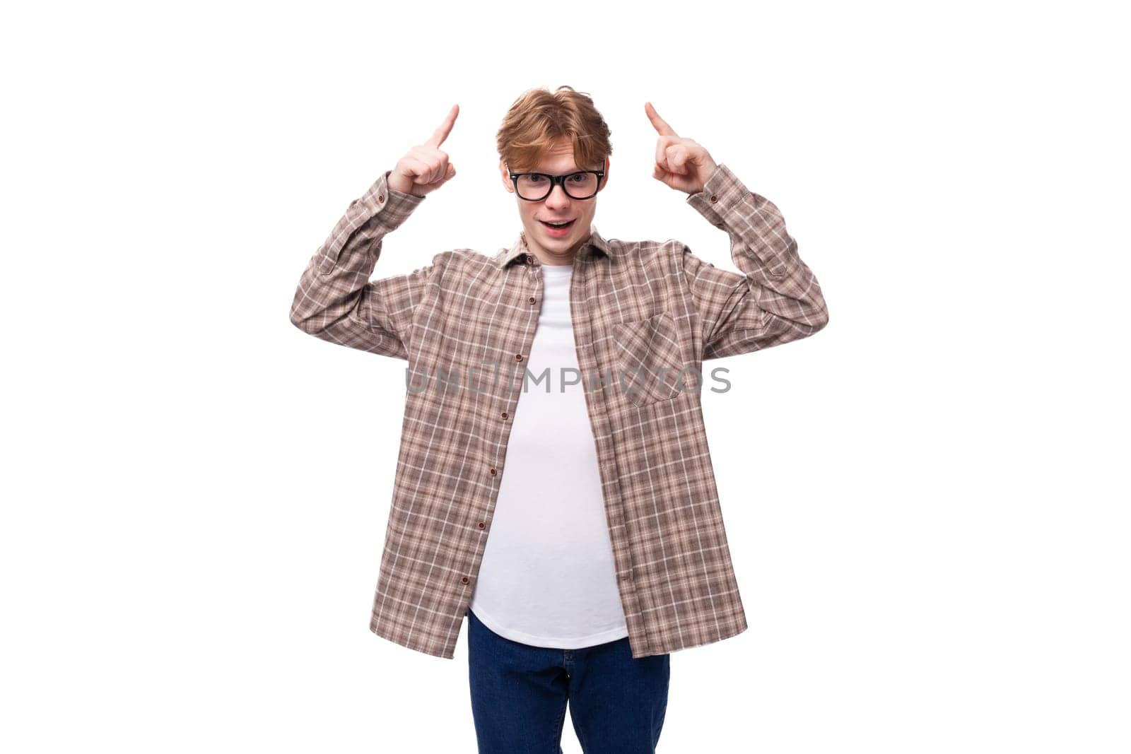 young joyful red-haired guy with glasses in a plaid shirt on a white background.