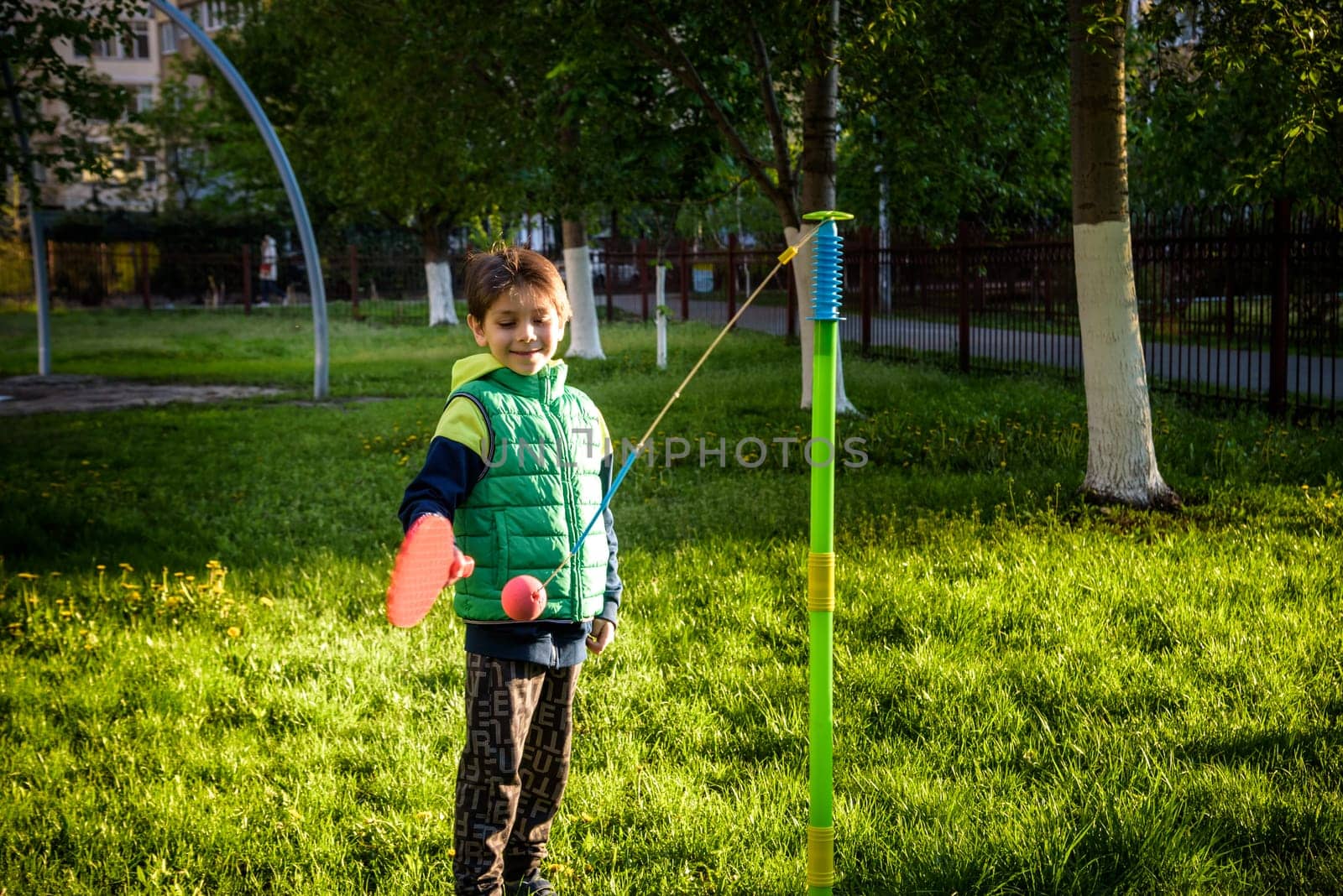 Happy boy is playing tetherball swing ball game in summer camping. Happy leisure healthy active time outdoors concept by Kobysh