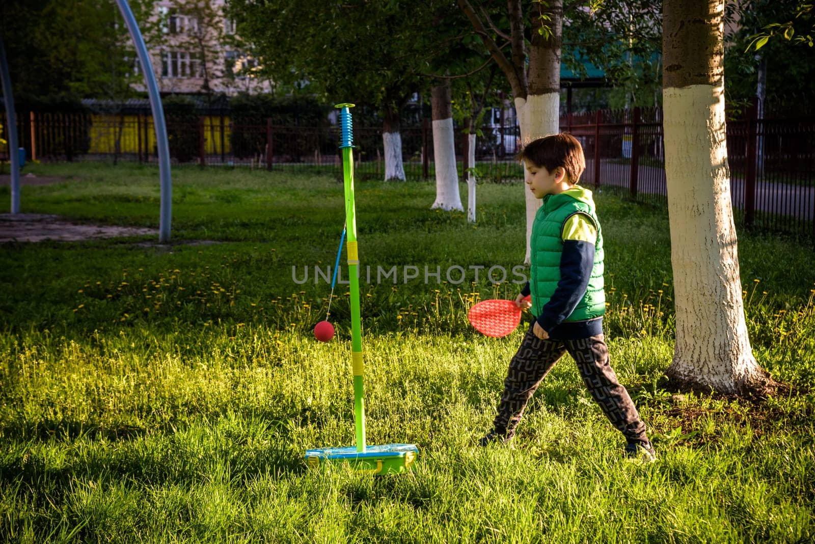 Happy boy is playing tetherball swing ball game in summer camping. Happy leisure healthy active time outdoors concept by Kobysh