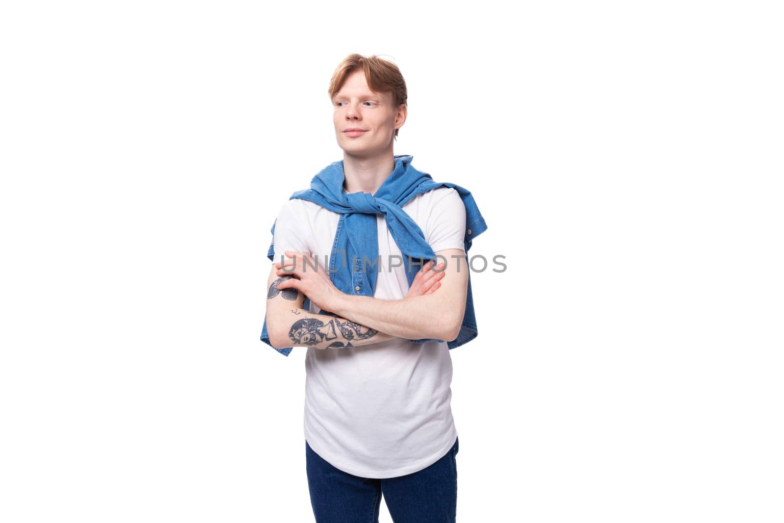 young well-groomed slender red-haired man in a stylish blue shirt on a white background with copy space by TRMK