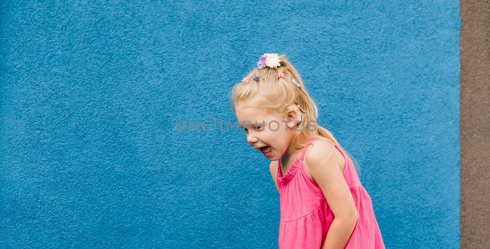 Banner Child girl walks and have fun outdoor with cochlear implant on the head. Hearing aid and treatment concept. Copy space. Inclusion and people with disability by Satura86