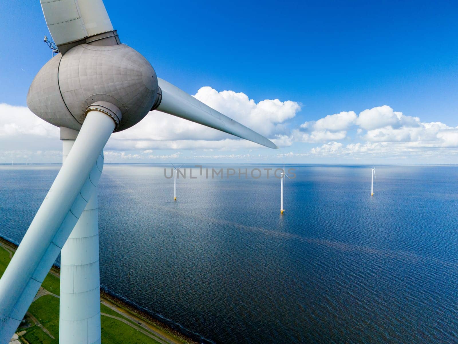 A wind turbine stands tall in the vast ocean, its blades gracefully spinning in the spring breeze, harnessing the power of the wind to generate clean energy by fokkebok