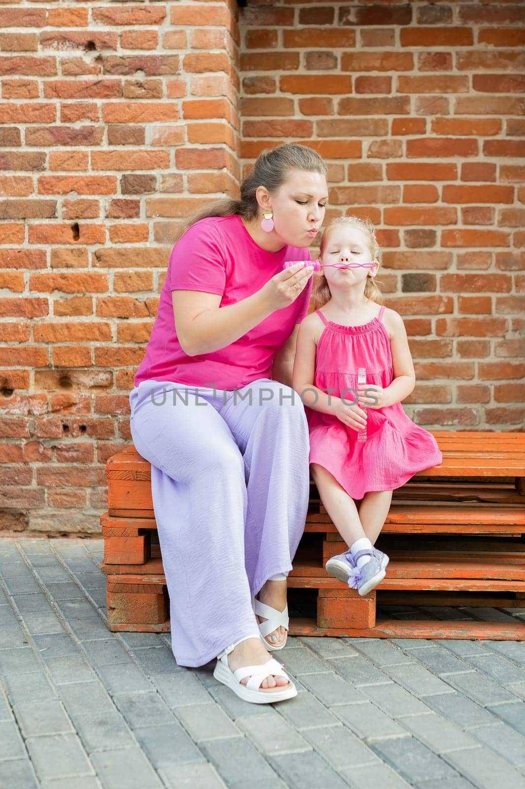 Deaf child with cochlear implant for hearing audio and aid for impairment having fun and laughs with mother outdoor in summer. Sound fitting device to help with communication listening and interaction. Inclusion and people with disability concept. by Satura86