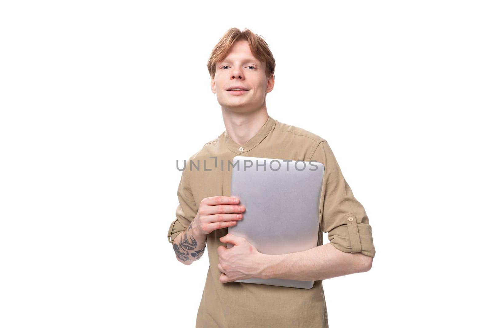 young red-haired man with glasses dressed in a brown shirt uses a laptop for study.